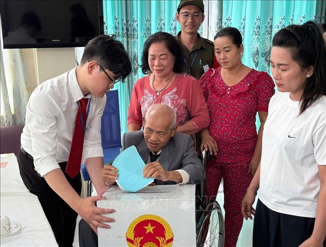 Cử tri Nguyễn Ngọc Anh (sinh năm 1945) xúc động khi được các cán bộ hỗ trợ bỏ phiếu tại nhà. Ảnh: Hữu Duyên - TTXVN