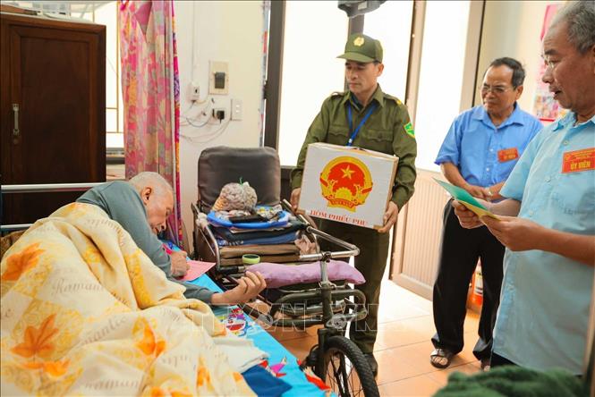 Tổ bầu cử đưa phiếu bầu và hòm phiếu phụ đến để cử tri Đỗ Văn Thế (sinh năm 1944, thương binh hạng ¼, tỷ lệ thương tật 91%) thực hiện quyền công dân. Ảnh: Hoàng Hiếu - TTXVN