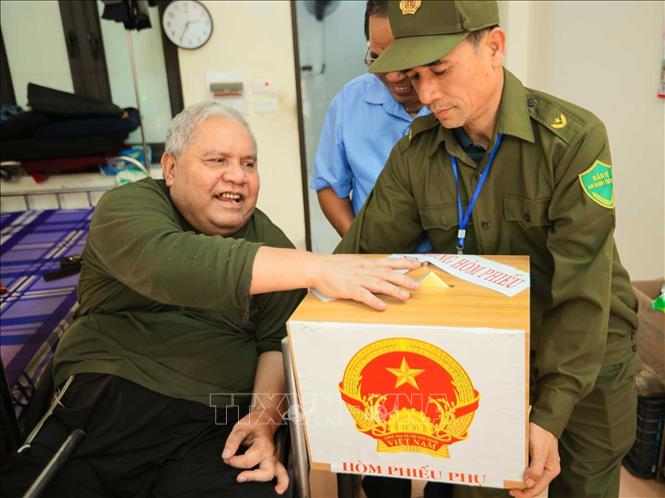 Cử tri Dương Đức Quang (sinh năm 1961, thương binh hạng ¼, tỷ lệ thương tật 95%) bỏ phiếu vào hòm phiếu phụ. Ảnh: Hoàng Hiếu - TTXVN 