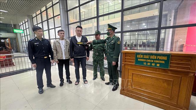 Đối tượng SHI JIAXING (Thạch Gia Hưng, áo đen đứng giữa) bị lực lượng chức năng Cửa khẩu quốc tế Móng Cái bắt giữ. Ảnh: TTXVN phát
