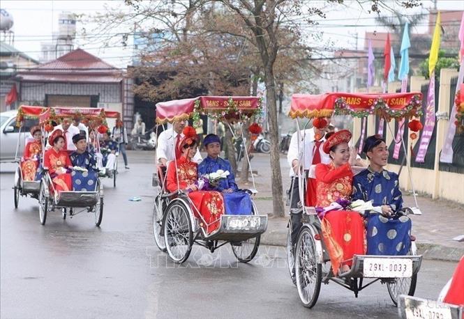 Hạnh phúc của các cặp đôi cô dâu chú rể đến hôn trường bằng xe xích lô trong lễ cưới tập thể theo nếp sống văn minh tại Hà Nội. Ảnh: Dương Giang - TTXVN
