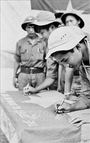 Các chiến sĩ tổ mở cửa quân giải phóng Quảng Ngãi ký tên lên lá cờ thề quyết tử giành giữ quê hương, trước khi mở màn vào chiến dịch mùa Xuân 1975. Ảnh: Thanh Tụng – TTXVN