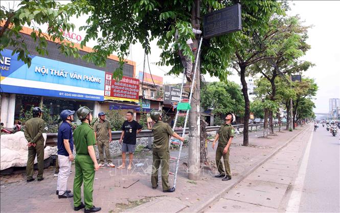 Tổ công tác của phường Phương Liệt tổ chức tháo dỡ các biển quảng cao đặt sai quy định tại tuyến đường Giải Phóng. Ảnh: Phạm Kiên - TTXVN