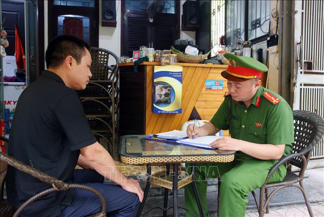 Công an phường Phương Liệt lập biên bản xử phạt một cơ sở kinh doanh đồ uống về lỗi lấn chiếm vỉa hè. Ảnh: Phạm Kiên - TTXVN