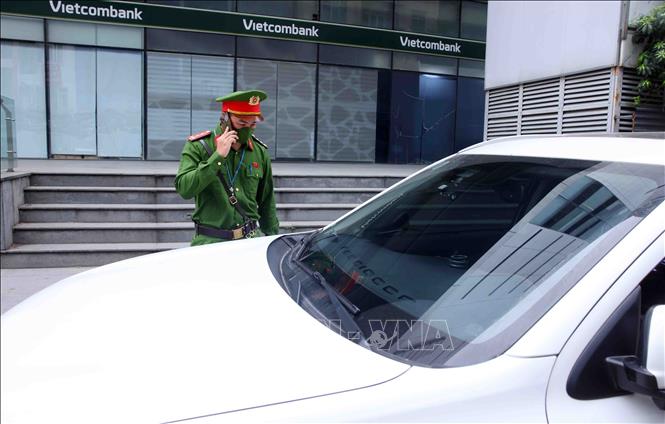 Cán bộ, chiến sĩ Công an phường Phương Liệt liên lạc với chủ phương tiện giao thông vi phạm lỗi dừng, đỗ sai quy định trên tuyến phố Lê Trọng Tấn. Ảnh: Phạm Kiên - TTXVN