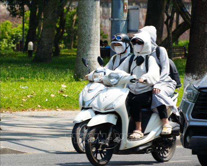 Người dân thành phố Huế mặc đồ bảo hộ chống nắng, khi di chuyển trên đường Lê Duẩn, phường Phú Xuân. Ảnh: Nguyên Lý - TTXVN