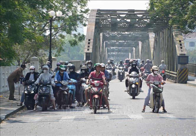 Người dân thành phố Huế mặc đồ bảo hộ chống nắng khi, di chuyển ở phía Bắc cầu Trường Tiền, phường Phú Xuân. Ảnh: Nguyên Lý - TTXVN