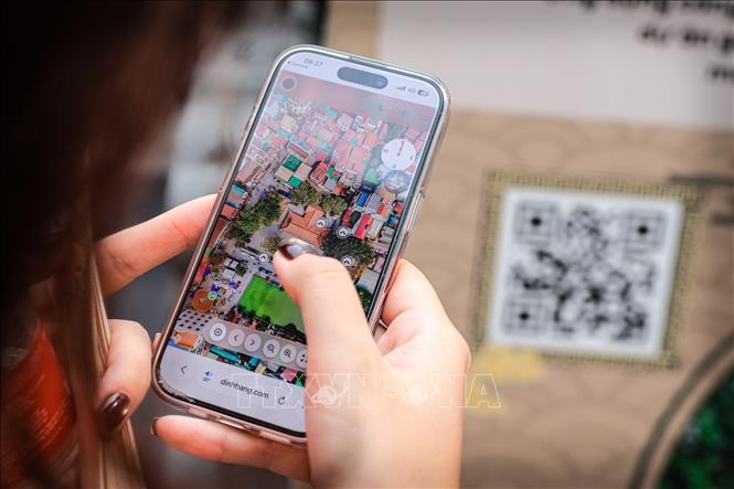 Du khách sử dụng điện thoại quét mã và trải nghiệm bản đồ số 360 độ để tham quan di tích Đền Đô. Ảnh: Phạm Tuấn Anh - TTXVN
