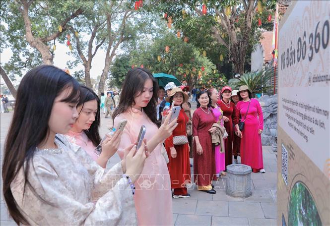 Các bạn trẻ sử dụng điện thoại thông minh truy cập thông tin số hóa về di tích và hành trình tham quan. Ảnh: Phan Phương - TTXVN