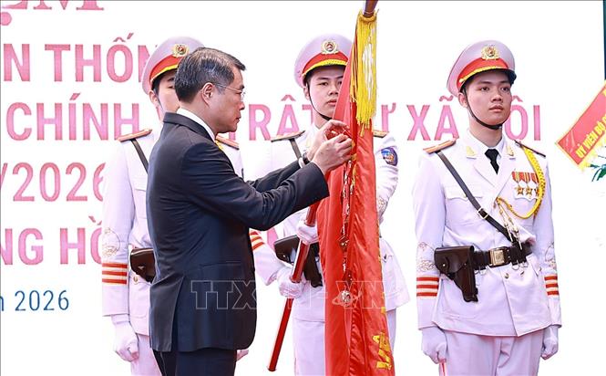 Thủ tướng Lê Minh Hưng gắn Huân chương Hồ Chí Minh lên Cờ truyền thống của lực lượng Cảnh sát QLHC về TTXH. Ảnh: Dương Giang-TTXVN 
