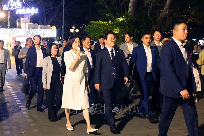Tổng thống Hàn Quốc Lee Jae Myung và Phu nhân Kim Hae Kyung vừa ăn kem Thuỷ Tạ vừa đi dạo quanh hồ Hoàn Kiếm. Ảnh: Phạm Kiên - TTXVN
