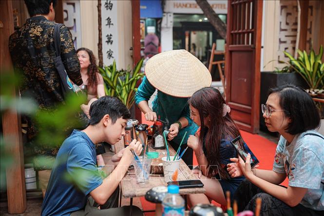 Người tham gia trực tiếp thực hành trang trí sản phẩm sơn mài dưới sự hướng dẫn của nghệ nhân. Ảnh: Phạm Tuấn Anh - TTXVN