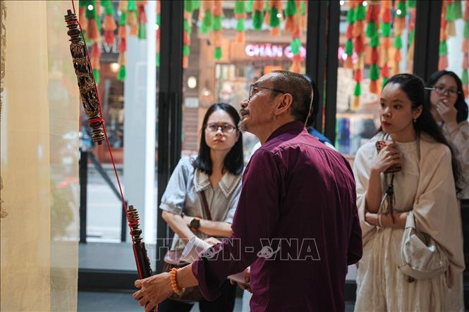 Nhà nghiên cứu Đàm Quang Minh giới thiệu về kỹ thuật và ý nghĩa của các tác phẩm sơn ta tới khách tham quan. Ảnh: Phạm Tuấn Anh - TTXVN
