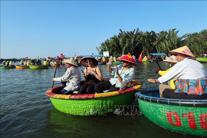 Foreign tourists are excited to experience basket boat trips at Cam Thanh village. VNA Photo: Đỗ Trưởng