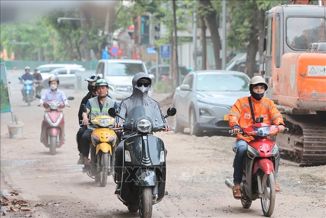 Bụi từ công trường thi công cống ngầm trên phố Quang Trung ảnh hưởng đến tầm nhìn, khiến người tham gia giao thông phải che chắn và di chuyển thận trọng. Ảnh: Lê Đông - TTXVN