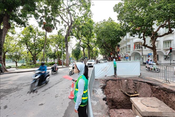 Đơn vị thi công bố trí nhân viên phân luồng giao thông tại khu vực ngã tư Hàng Khay - Tràng Thi, nhằm bảo đảm an toàn cho người và phương tiện trong thời gian thi công hệ thống cống ngầm. Ảnh: Lê Đông - TTXVN