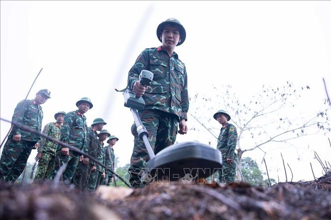 Các thành viên Đội tìm kiếm, quy tập hài cốt liệt sĩ tìm hiểu, sử dụng thành thục máy dò mìn để đảm bảo sạch bom mìn, vật liệu nổ trong khu vực trước khi tiến hành tìm kiếm. Ảnh: Hoàng Hiếu - TTXVN