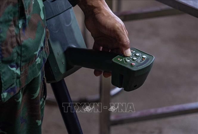Thiếu tá quân nhân chuyên nghiệp Lê Văn Quyết hướng dẫn các thành viên trong Đội sử dụng máy dò mìn, đảm bảo an toàn khi tìm kiếm. Ảnh: Hoàng Hiếu - TTXVN