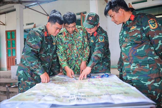 Thành viên đội trao đổi, xác định khu vực nghi có hài cốt liệt sĩ theo thông tin thân nhân liệt sĩ cung cấp. Ảnh: Hoàng Hiếu - TTXVN 