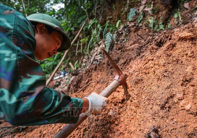 Các thành viên Đội tiến hành tìm kiếm tại khu vực nghi có hài cốt liệt sĩ tại xã Minh Tân. Ảnh: Hoàng Hiếu - TTXVN