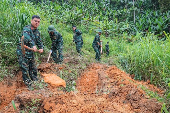 Các thành viên Đội tiến hành tìm kiếm tại khu vực nghi có hài cốt liệt sĩ tại xã Minh Tân. Ảnh: Hoàng Hiếu - TTXVN