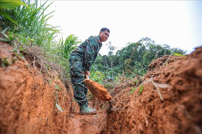 Các thành viên Đội tiến hành tìm kiếm tại khu vực nghi có hài cốt liệt sĩ tại xã Minh Tân. Ảnh: Hoàng Hiếu - TTXVN