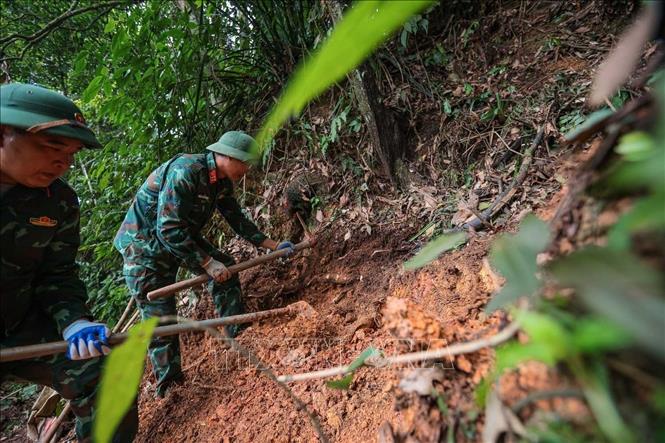 Các thành viên Đội tiến hành tìm kiếm tại khu vực nghi có hài cốt liệt sĩ tại xã Minh Tân. Ảnh: Hoàng Hiếu - TTXVN