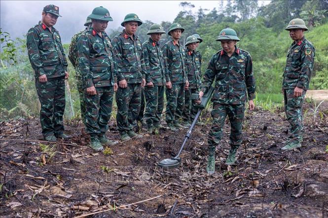 Các thành viên Đội tìm kiếm, quy tập hài cốt liệt sĩ tìm hiểu, sử dụng thành thục máy dò mìn để đảm bảo sạch bom mìn, vật liệu nổ trong khu vực trước khi tiến hành tìm kiếm. Ảnh: Hoàng Hiếu - TTXVN