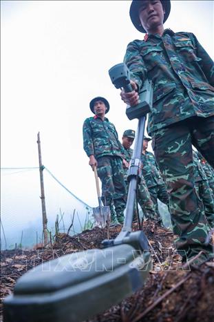 Các thành viên Đội tìm kiếm, quy tập hài cốt Liệt sĩ sử dụng máy dò mìn để đảm bảo khu vực tìm kiếm 