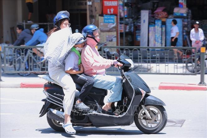 Che chắn chống nắng cho trẻ khi phải di chuyển ngoài trời. Ảnh: Hoàng Hiếu - TTXVN 