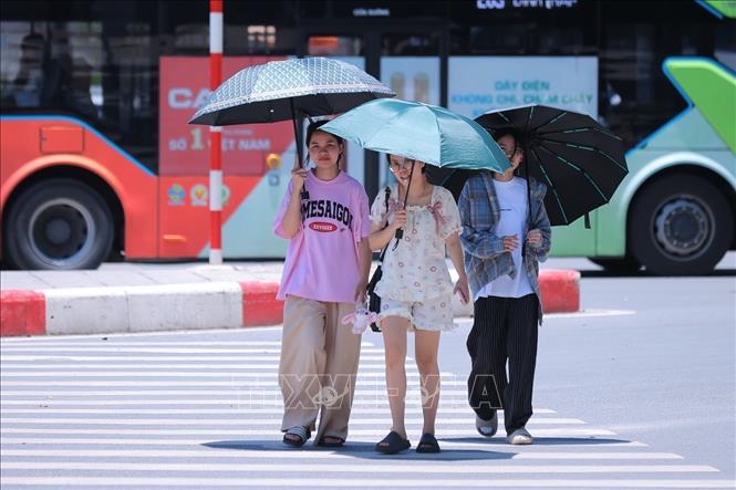 Người dân tìm mọi cách che chắn chống nắng, nóng khi phải di chuyển trên đường Tây Sơn. Ảnh: Hoàng Hiếu - TTXVN 