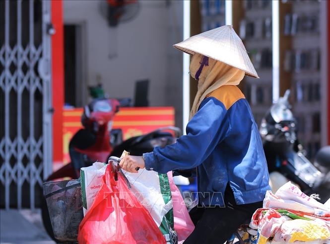 Một người lao động che chắn kỹ khi phải làm việc ngoài trời. Ảnh: Hoàng Hiếu - TTXVN