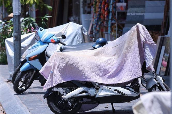 Nhiều chủ xe che chắn xe máy khi nhiệt độ ngoài trời của Hà Nội vượt ngưỡng 40 độ C. Ảnh: Hoàng Hiếu - TTXVN