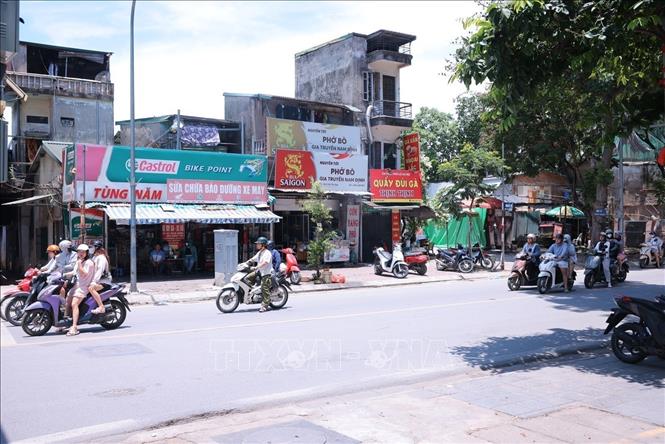 Giữa nền nhiệt ngoài trời vượt 40 độ C, nhiều người dân lựa chọn đứng dưới bóng cây, bóng râm ven đường để tránh nắng trong thời gian chờ đèn đỏ. Ảnh: Hoàng Hiếu - TTXVN