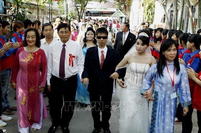 Lãnh đạo Trung tâm Nhân đạo Quê Hương, tỉnh Bình Dương (bên trái) tổ chức lễ cưới tập thể cho 12 cặp vợ chồng là nạn nhân chất độc da cam/điôxin, khiếm thị và khuyết tật vận động, hiện đang sinh sống và làm việc tại Trung tâm (2014). Ảnh: Thế Anh - TTXVN