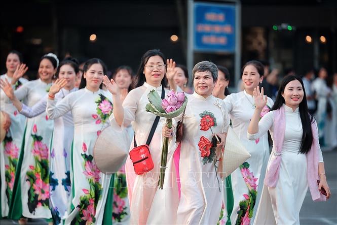 Những tà áo dài trắng thêu họa tiết sen cùng hoa sen cầm tay tại lễ diễu hành. Ảnh: Phạm Tuấn Anh - TTXVN