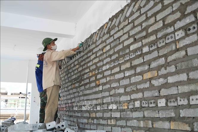 Các tổ đội thi công khẩn trương hoàn thiện phần xây, trát tường tại khu nhà học. Ảnh: Hữu Quyết – TTXVN