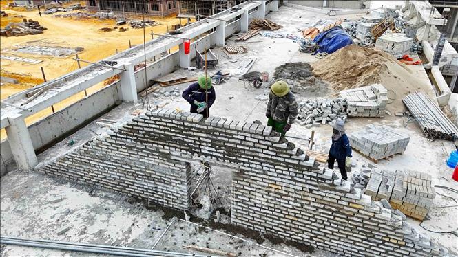 Công nhân tập trung thi công khối nhà học THCS 3 tầng, một trong những hạng mục trọng điểm của dự án. Ảnh: Hữu Quyết – TTXVN