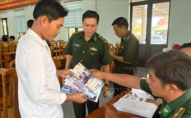 Cán bộ Đồn Biên phòng Lý Hòa cấp phát tờ rơi tuyên truyền, phổ biến những quy định mới của pháp luật. Ảnh: Võ Dung - TTXVN