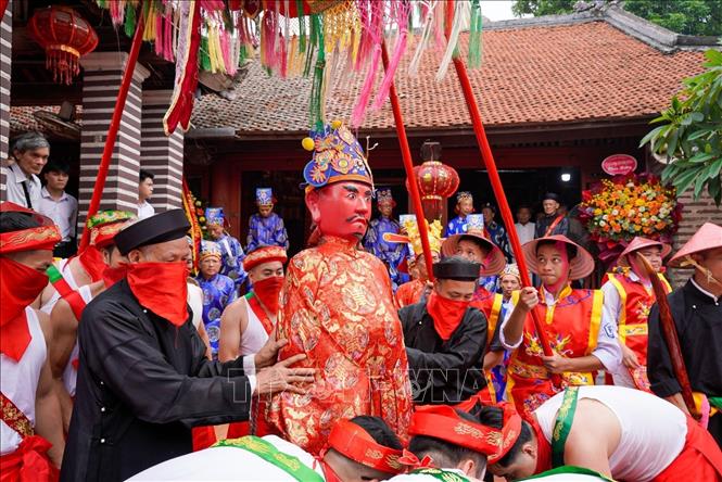 Tượng thánh được đưa ra khu vực sân đình một cách cẩn thận để bắt đầu nghi lễ mộc dục với đội phù giá hùng hậu. Ảnh: Khánh Hoà - TTXVN