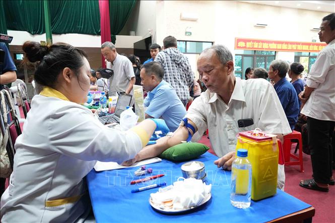 Thân nhân liệt sĩ được hướng dẫn từng bước trong quá trình thu nhận mẫu sinh phẩm ADN. Ảnh: Hữu Quyết - TTXVN