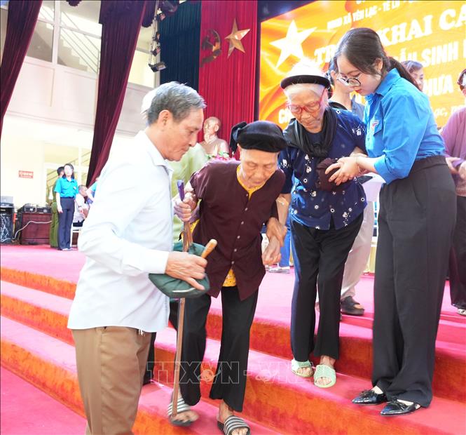 Thanh niên tình nguyện hỗ trợ các thân nhân liệt sĩ đến điểm thu nhận mẫu ADN. Ảnh: Nguyễn Thảo - TTXVN