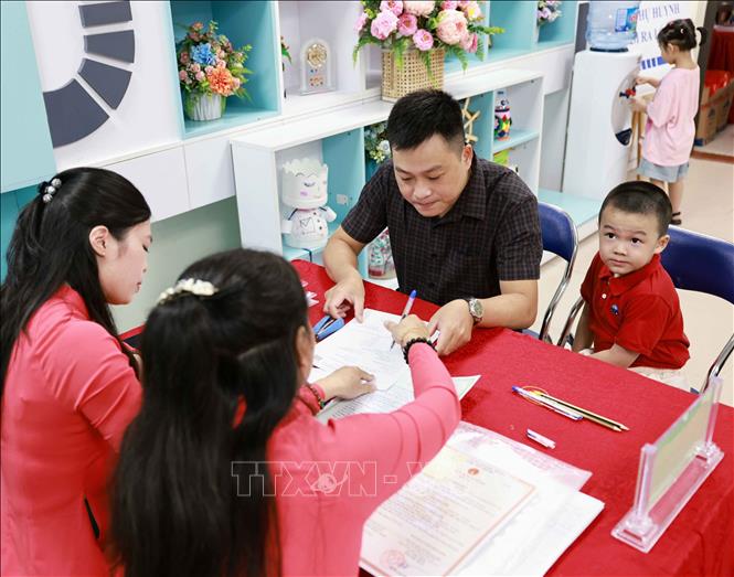 Trẻ háo hức khi được cùng bố mẹ tới ngôi trường em được vào lớp 1 trong thời gian nhà trường tuyển sinh trực tiếp. Ảnh: Thanh Tùng - TTXVN