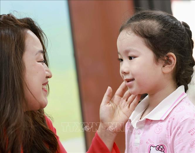 Một chút bẽn lẽn, ngây thơ và đáng yêu của trẻ bên cô giáo Trường Tiểu học Thăng Long (phường Hoàn Kiếm). Ảnh: Thanh Tùng - TTXVN