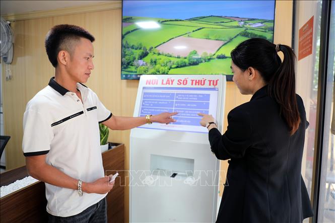 Hướng dẫn người dân lấy số thứ tự tự động. Ảnh: Tạ Toàn – TTXVN