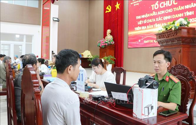 Cán bộ Công an thu nhận mẫu ADN thân nhân liệt sĩ chưa xác định danh tính. Ảnh: Văn Sĩ - TTXVN 