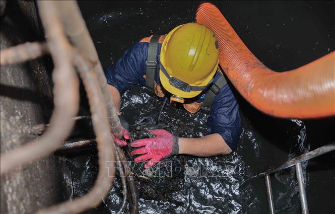 Trực tiếp ngâm mình dưới dòng nước cống đen ngòm để khơi thông dòng chảy, đảm bảo cuộc sống bình yên cho người dân Thủ đô. Ảnh: Phan Phương – TTXVN