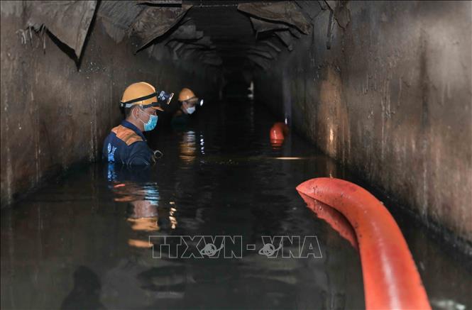 Ngâm mình dưới dòng nước đen ngòm để hút sạch bùn thải, khơi thông dòng chảy cho Thủ đô. Ảnh: Phan Phương – TTXVN