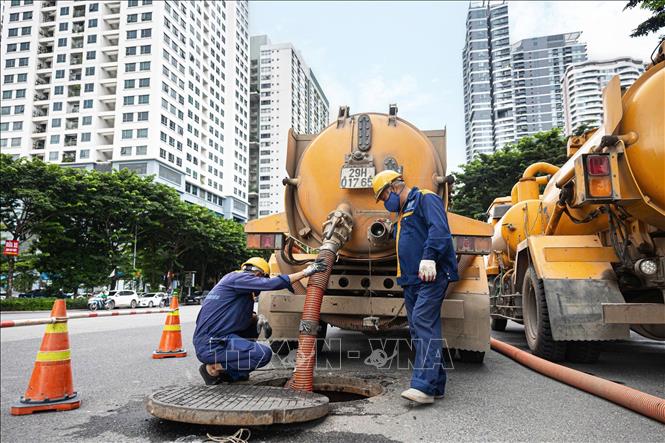 Công nhân trực tiếp xuống cống ngầm thu gom rác để vận chuyển về khu tập kết xử lý. Ảnh: Tiến Long/TTXVN phát