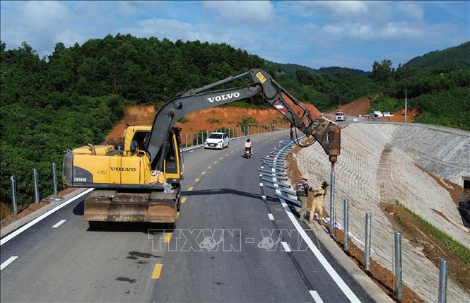 Triển khai thi công những hạng mục cuối cùng trên tuyến như lắp đặt tôn sóng hai bên đường, sơn kẻ làn đường và lắp đặt hệ thống chiếu sáng. Ảnh: Quốc khánh - TTXVN